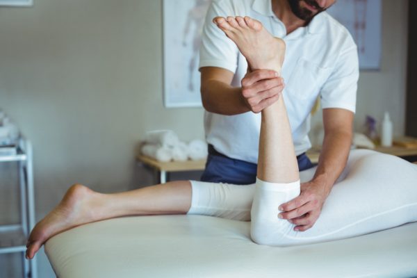 Physiotherapist giving leg massage to a woman